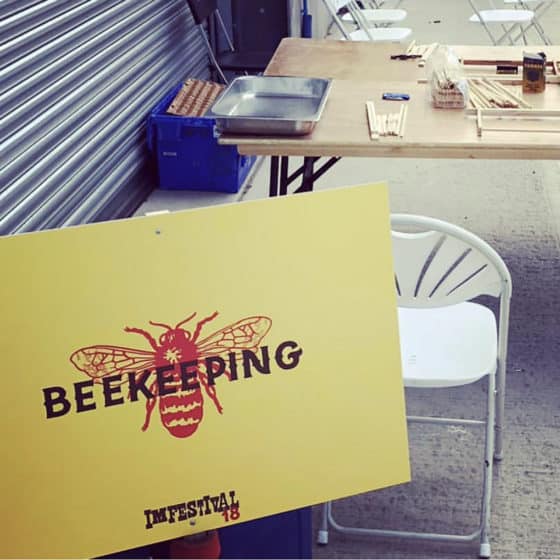 Beekeeping workshop setup with yellow sign and chairs.