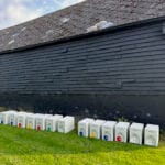 Row of white beehives on green grass